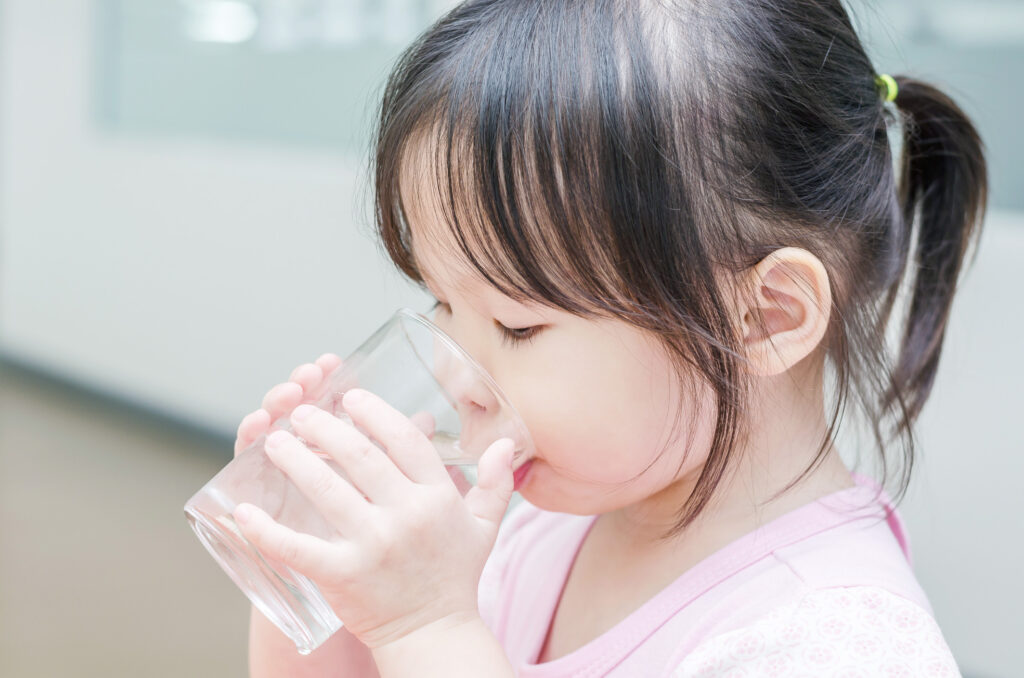 子供がコップで水を飲む様子