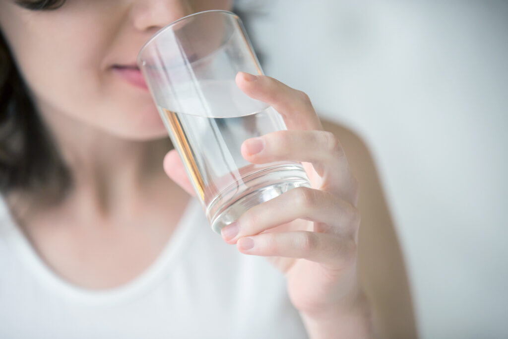 女性がガラスのコップで水を飲んでいる様子