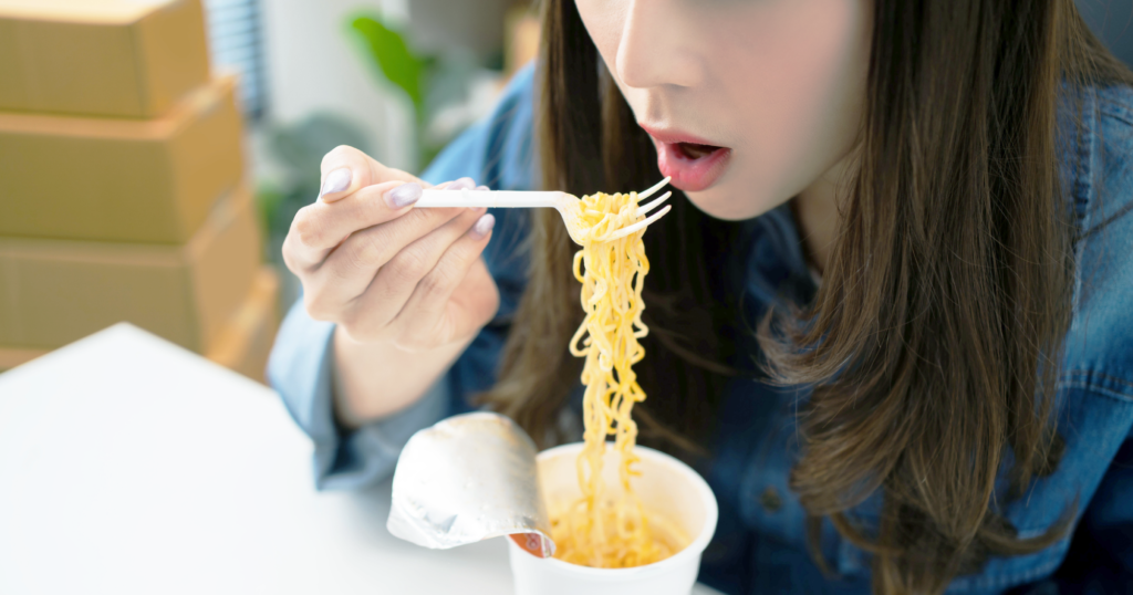 カップラーメンを女性が食べようとしている様子