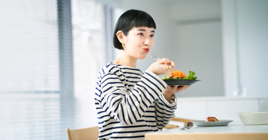 食卓でサラダを頬張る女性