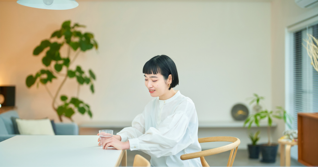 食卓でガラスに入った水を持つ女性