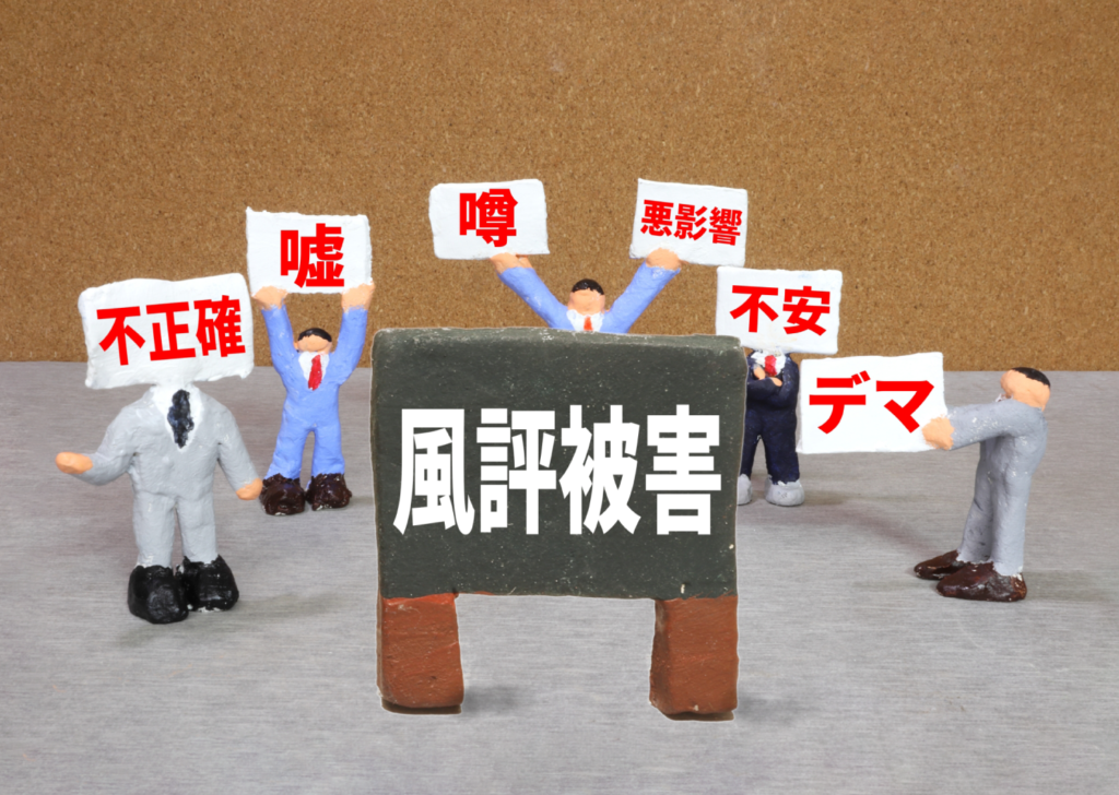 風評被害のイメージの紙粘土（スーツの男たちが「風評被害」を囲んでいる）