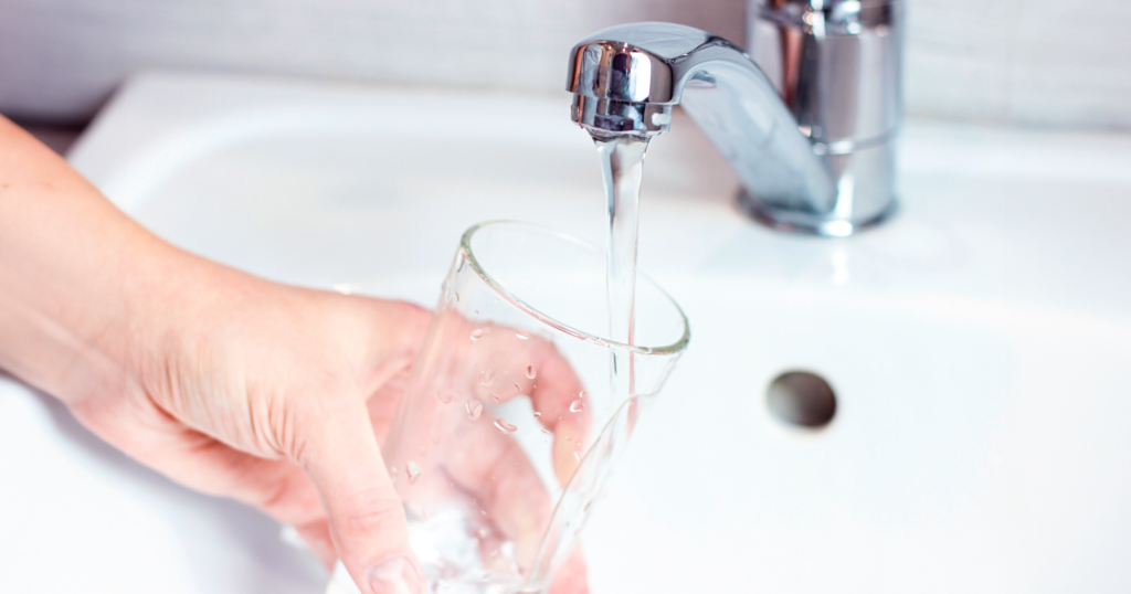 蛇口から出た水をガラスのコップに注いでいる様子